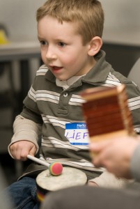 a young boy plays a small drum with mallets