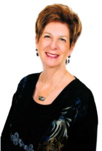 headshot of Judy Holstein smiling and wearing black