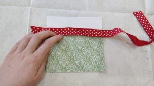 a decorative paper pocket with a piece of red ribbon across the lip of the pocket