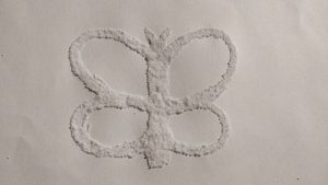 A glue butterfly with salt stuck to the glue.