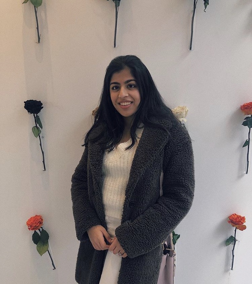 Pranavi standing in front of a wall with roses pinned to it.